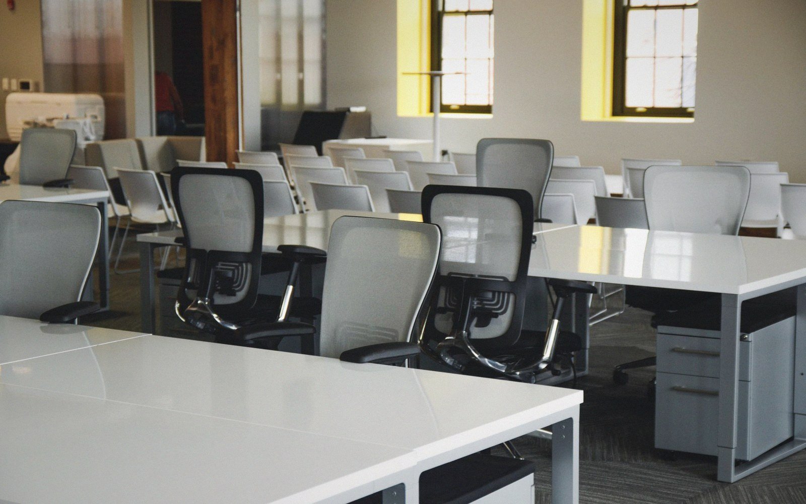 Empty office with mesh-back desk chairs and rows of stacked chairs behind